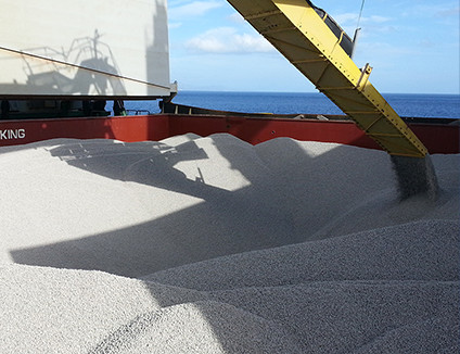 Załadunek sypkiego ładunku na statek handlowy za pomocą podajnika taśmowego